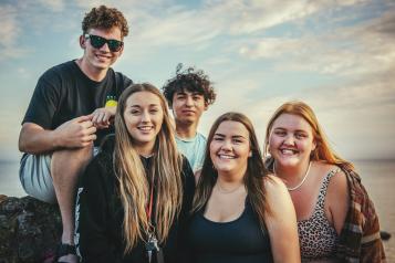 Group of young teenagers at the beach smiling at the camera