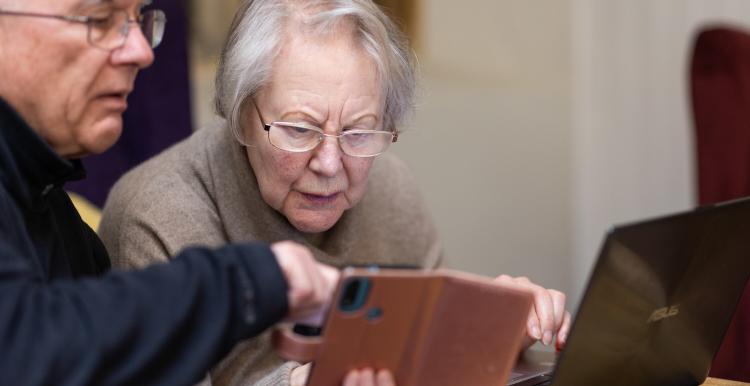 Older person learning how to use a mobile phone and laptop 