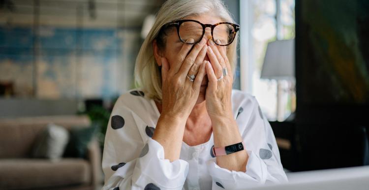 A lady feeling stressed, sitting with her head in her hands