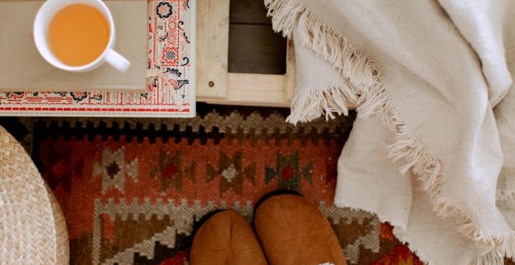 Image of someone in home, with slippers and a hot drink