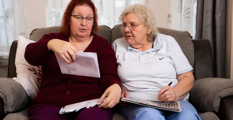 Two ladies reading a letter received from the hospital about an appointment 