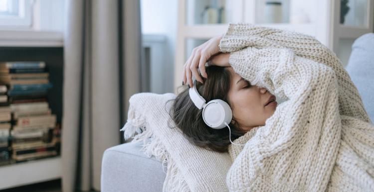 Lady lying on the couch listening to music 