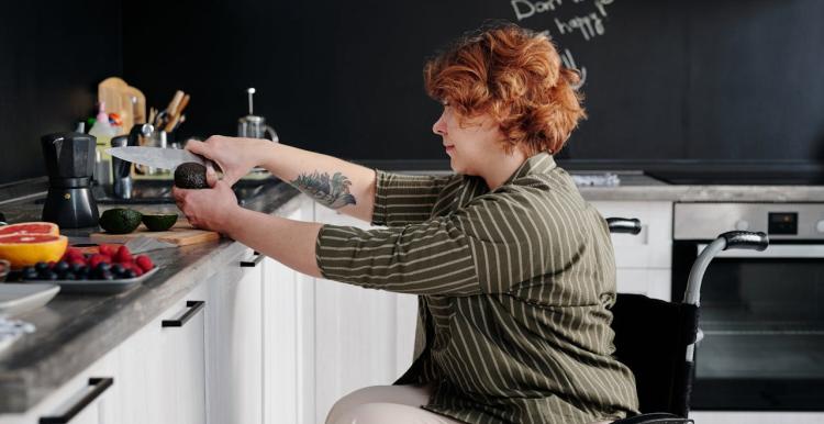 Lady in a wheelchair in her kitchen cutting fruit