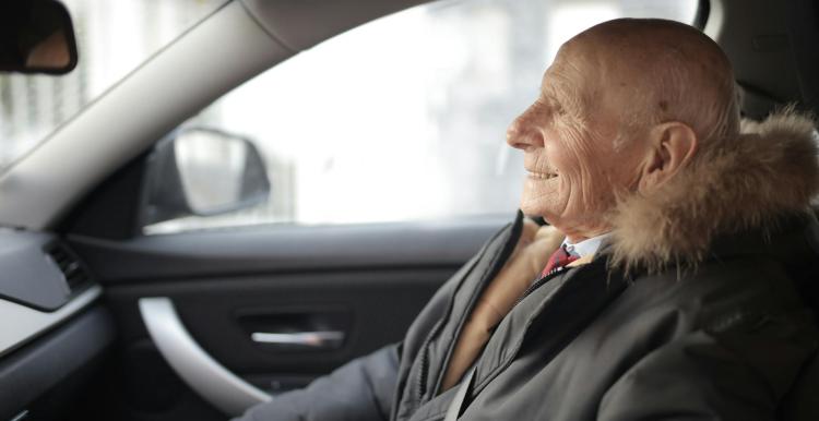 Older person in a thick coat sitting in a car