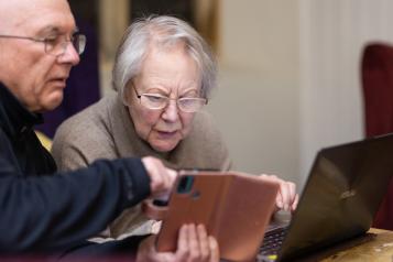 Older person learning how to use a mobile phone and laptop 