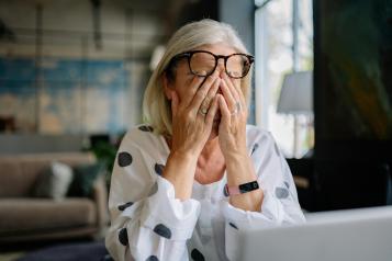 A lady feeling stressed, sitting with her head in her hands