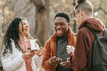 Three adults talking and laughing standing outside in a park during winter