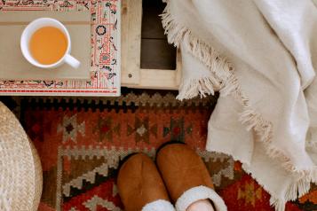 Image of someone in home, with slippers and a hot drink