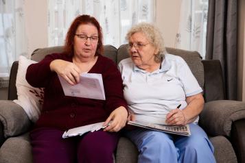 Two ladies reading a letter received from the hospital about an appointment 