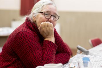 Older lady sitting at a table thinking and looking sad