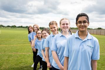 A group of youth volunteers standing in a line outside on a field