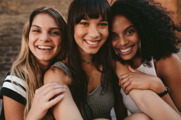 Three women sitting next to each other and smiling 