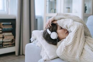 Lady lying on the couch listening to music 