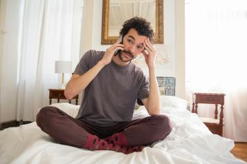 Man sitting on his bed talking on the phone