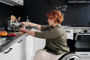 Lady in a wheelchair in her kitchen cutting fruit