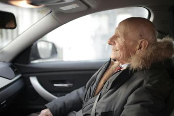 Older person in a thick coat sitting in a car